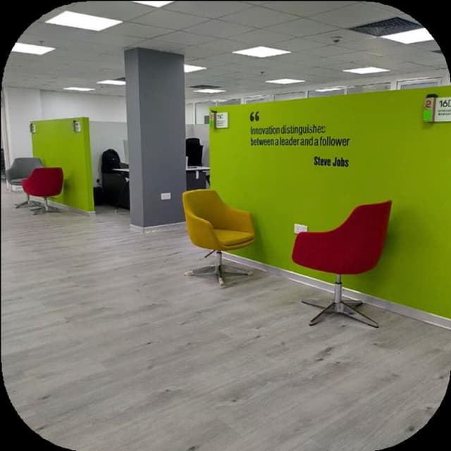 Open plan corporate workspace with desks and blue seating